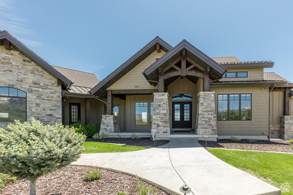 View of front facade with french doors, a standing seam roof, stone siding, and metal roof