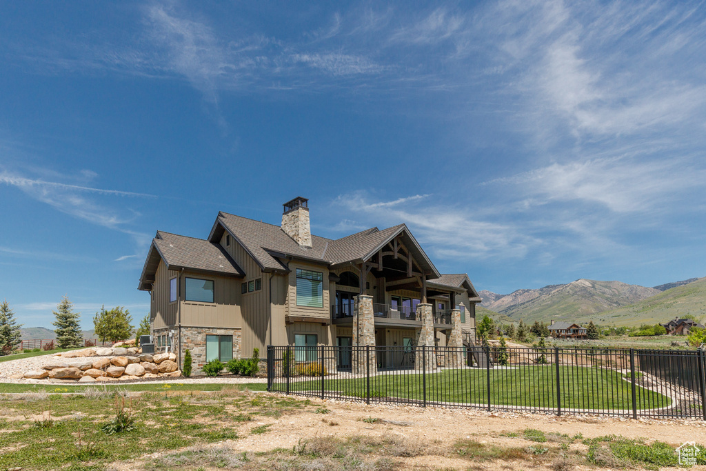 Rear view of property with a balcony, a mountain view, a chimney, stone siding, and roof with shingles