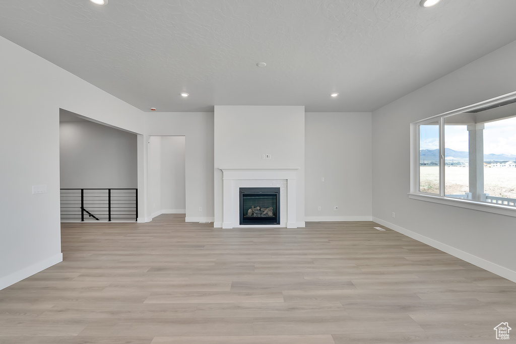 Unfurnished living room with recessed lighting, baseboards, light wood finished floors, and a fireplace