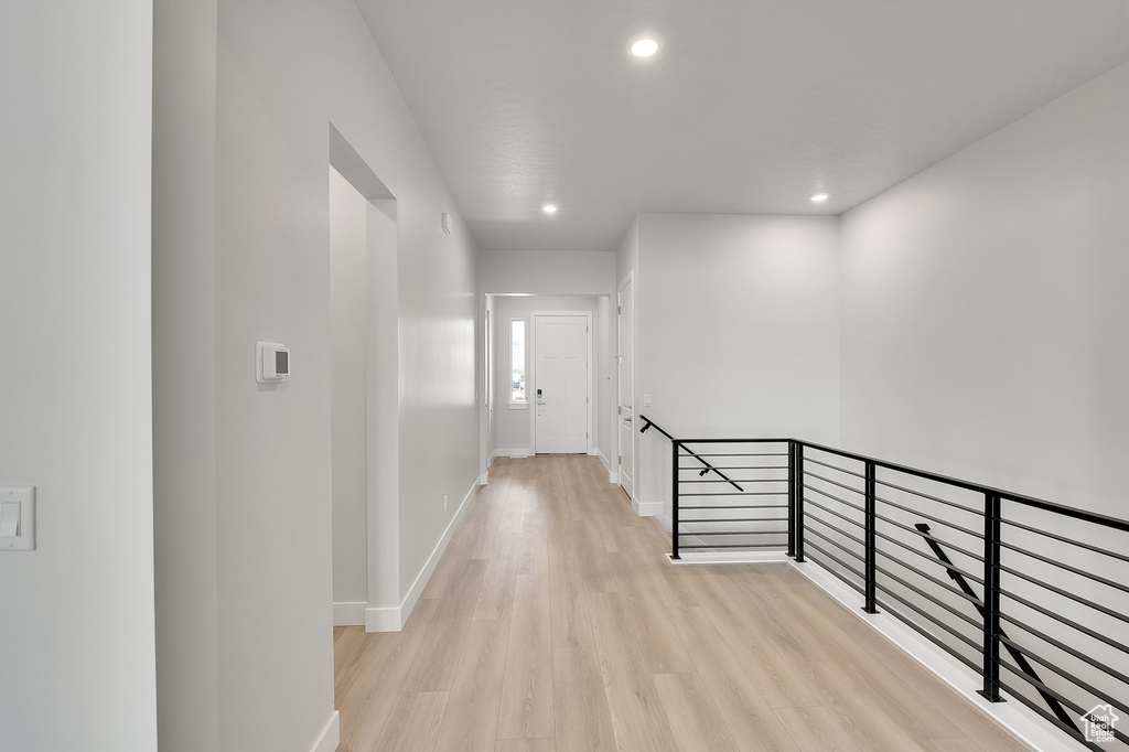 Hallway with an upstairs landing, light wood-style floors, recessed lighting, and baseboards