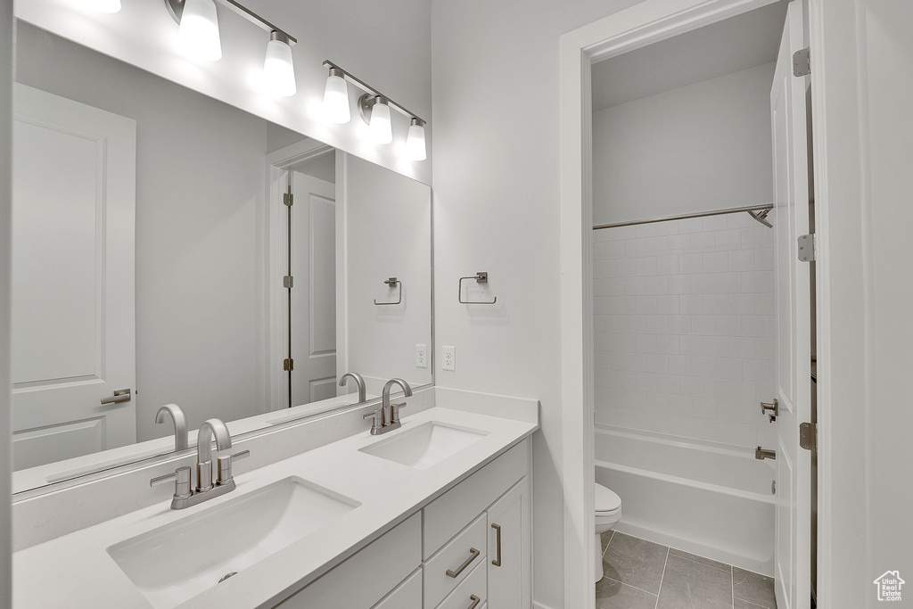 Full bath featuring toilet, double vanity, bathtub / shower combination, and tile patterned floors