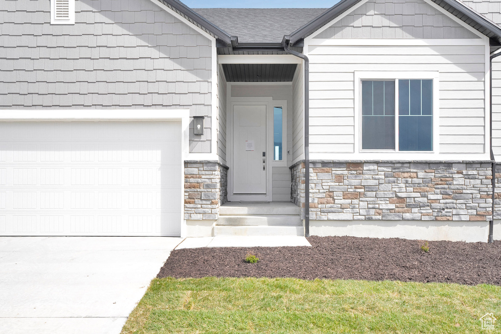 Property entrance with stone siding, concrete driveway, and an attached garage