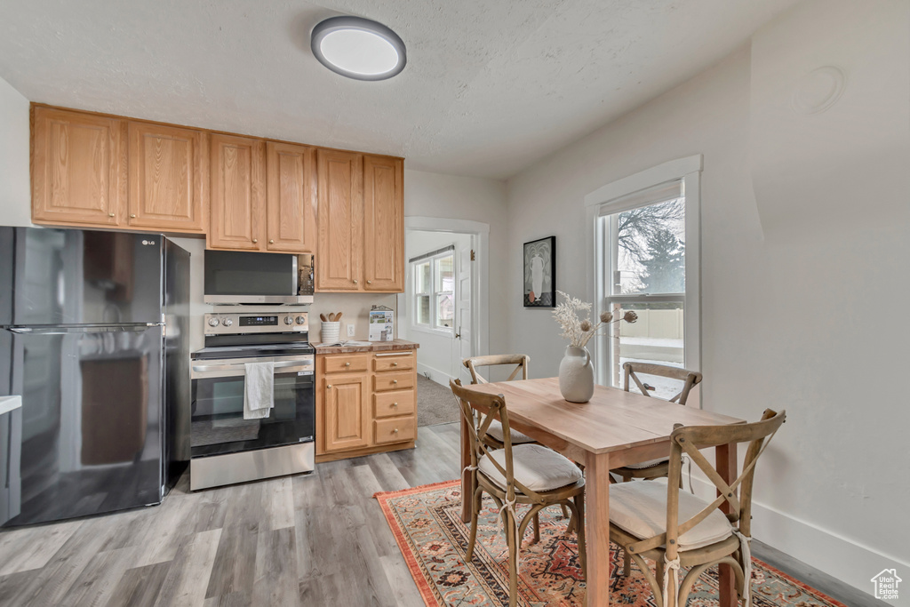 Kitchen featuring light wood-type flooring, baseboards, appliances with stainless steel finishes, and light countertops