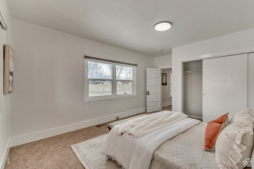 Bedroom with a closet, visible vents, carpet, and baseboards