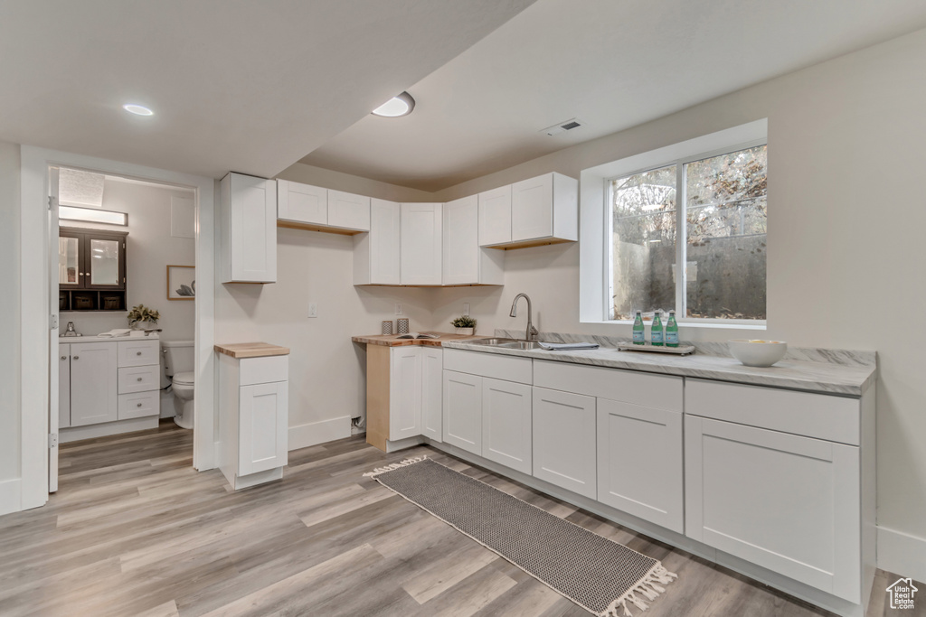 Kitchen with a sink, light wood-type flooring, and white cabinetry