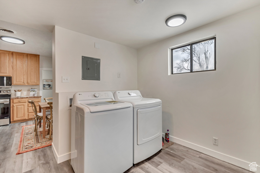 Laundry area with visible vents, baseboards, electric panel, separate washer and dryer, and light wood-style floors