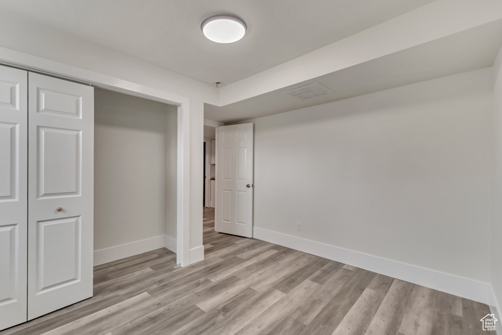 Unfurnished bedroom with light wood-style flooring, visible vents, baseboards, and a closet