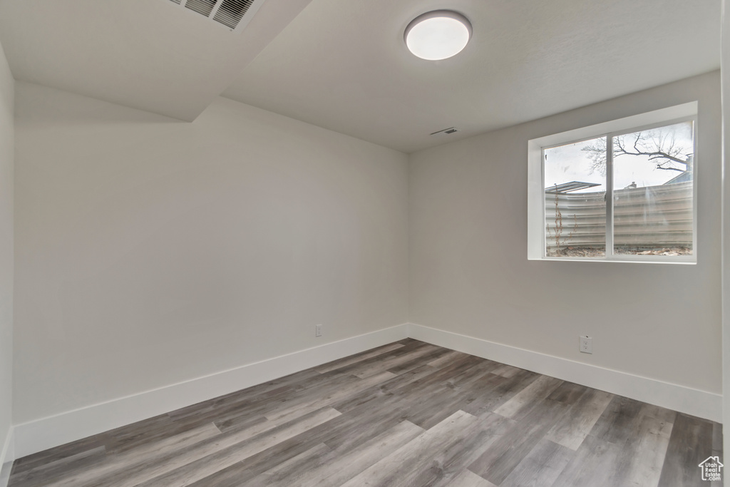 Spare room featuring visible vents, baseboards, and wood finished floors