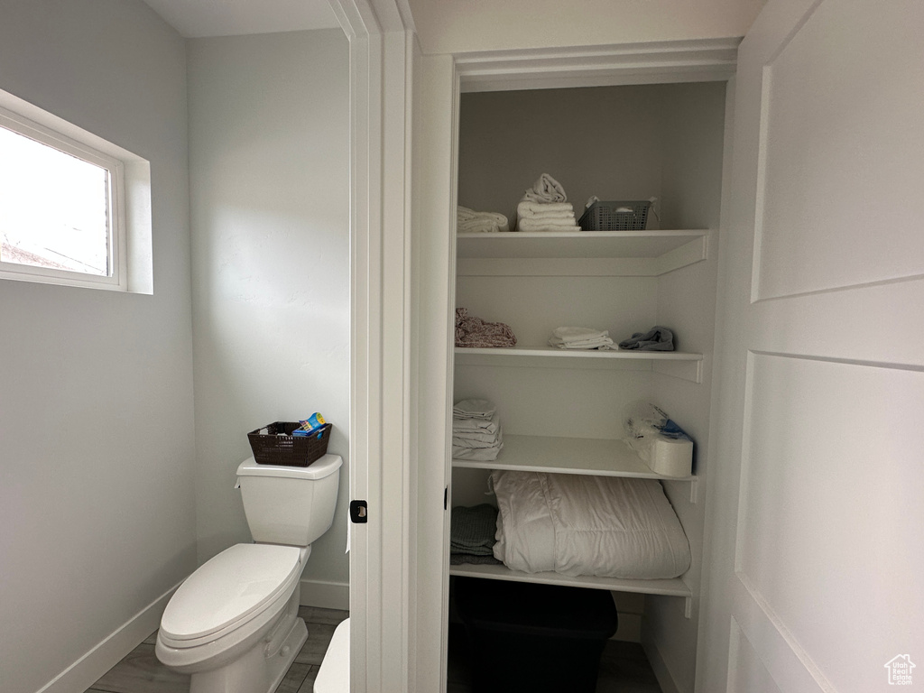 Bathroom featuring toilet, wood finished floors, and baseboards