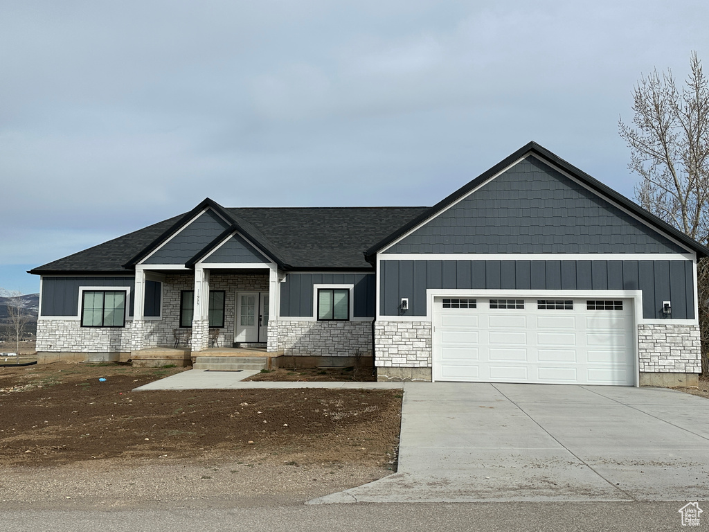 View of front of house with concrete driveway, an attached garage, board and batten siding, and roof with shingles