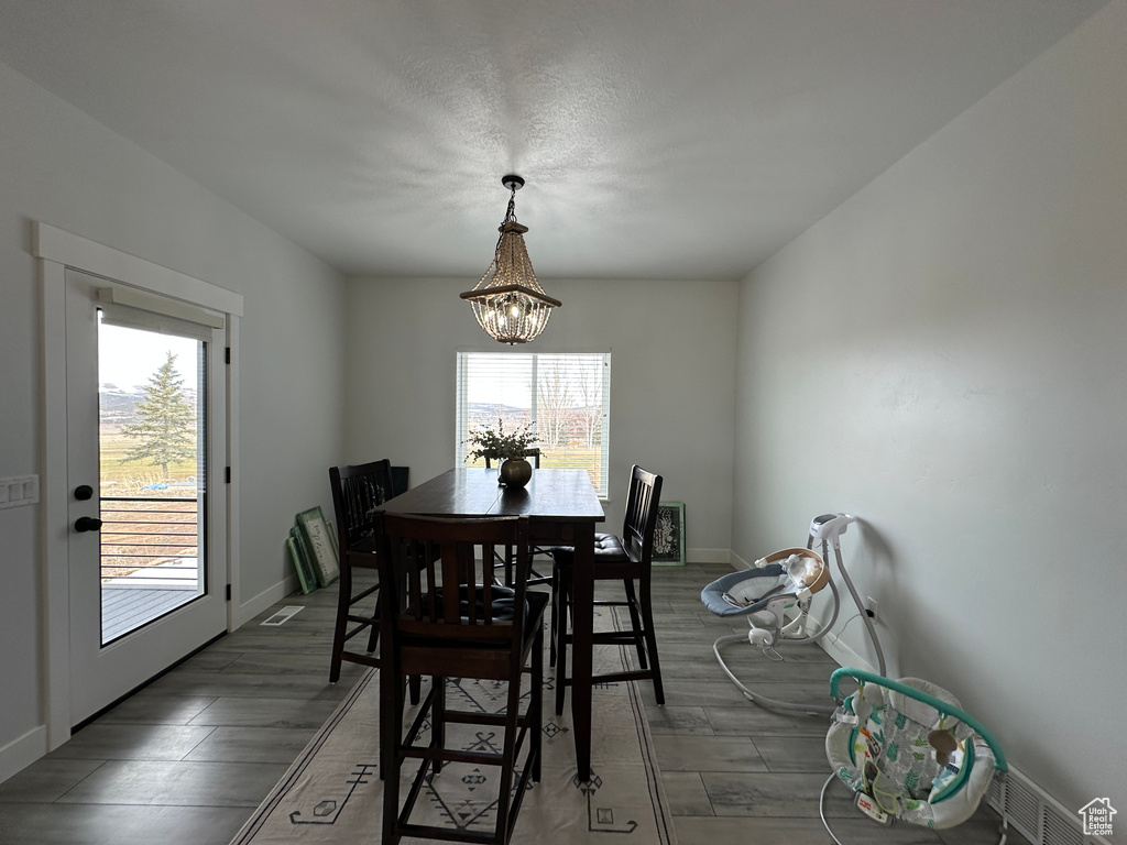 Dining room with a chandelier, visible vents, baseboards, and wood finished floors