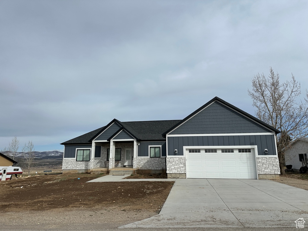 View of front of property featuring concrete driveway, a garage, board and batten siding, and stone siding