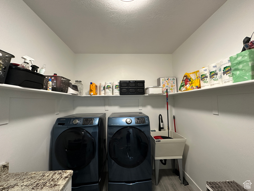 Laundry room featuring laundry area, wood finished floors, independent washer and dryer, and a textured ceiling