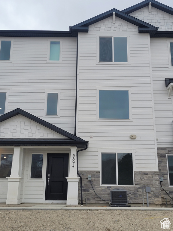 Rear view of house with stone siding and central AC