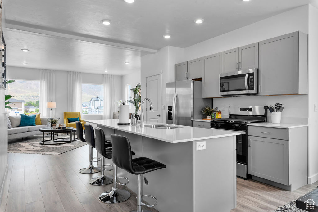 Kitchen with a breakfast bar area, gray cabinetry, stainless steel appliances, and a sink
