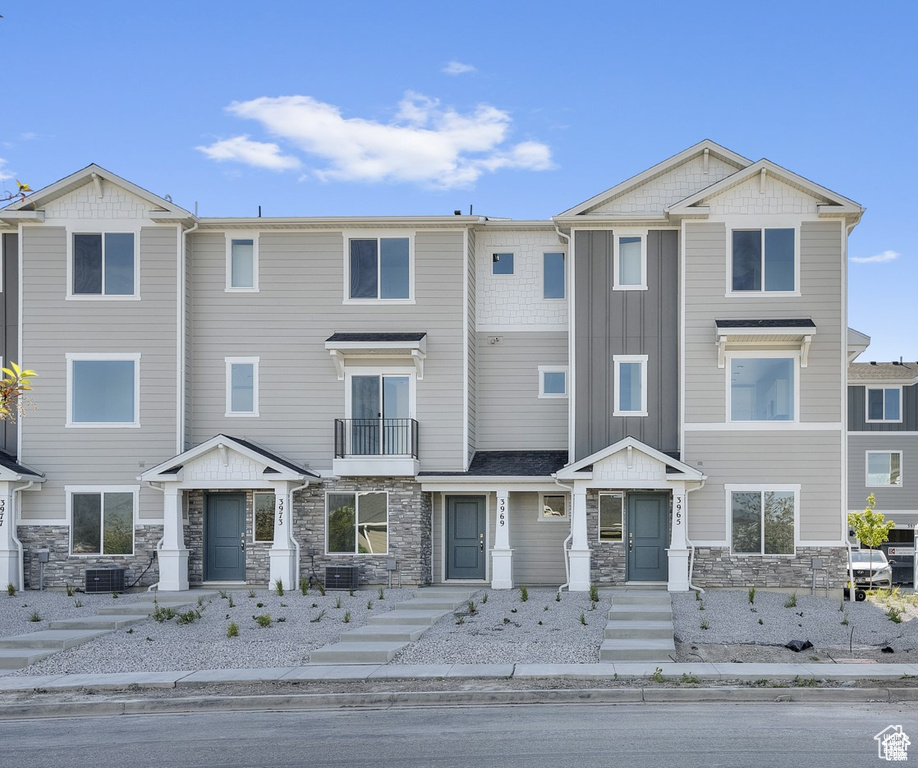 View of property with central air condition unit and stone siding