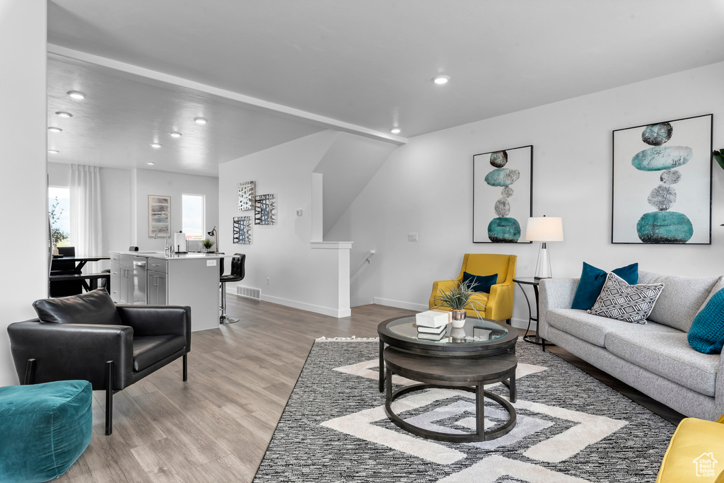 Living room with light wood finished floors, recessed lighting, and baseboards