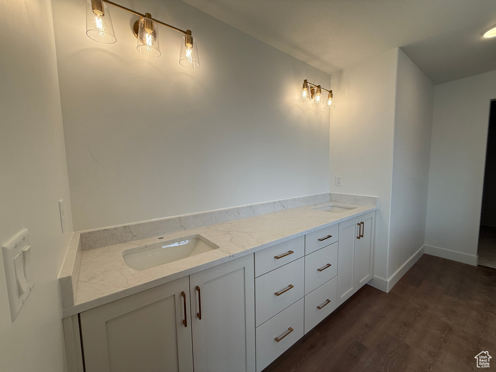 Bathroom featuring a sink, baseboards, wood finished floors, and double vanity