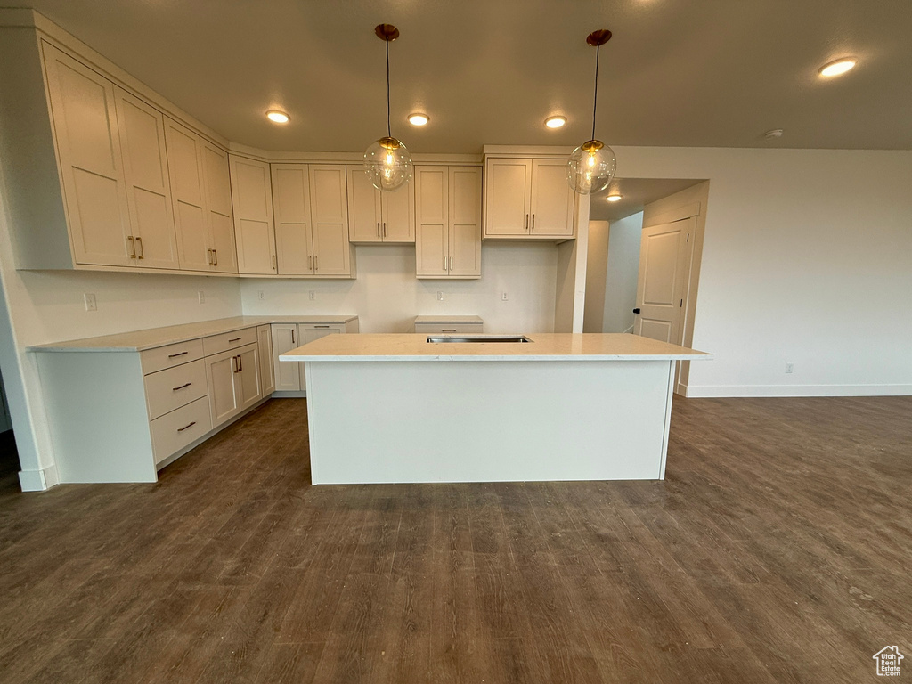 Kitchen with baseboards, recessed lighting, dark wood-type flooring, decorative light fixtures, and a center island
