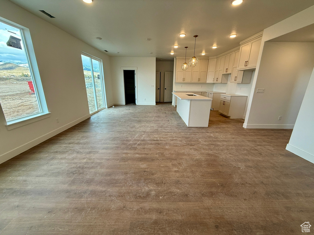 Kitchen featuring visible vents, open floor plan, a center island, white cabinetry, and baseboards