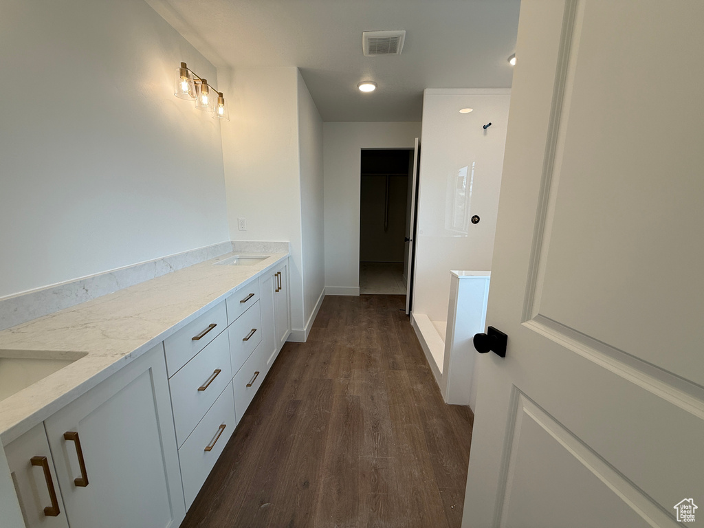 Full bathroom featuring wood finished floors, visible vents, baseboards, double vanity, and a sink