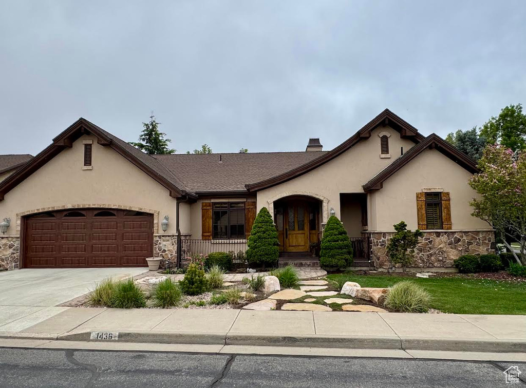 Ranch-style house featuring driveway, stone siding, a chimney, stucco siding, and a garage