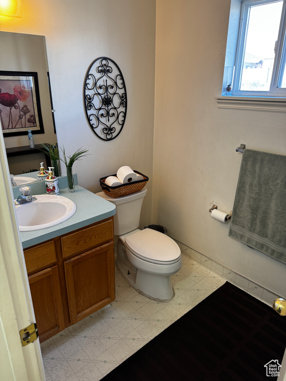 Half bath with tile patterned floors, toilet, and vanity