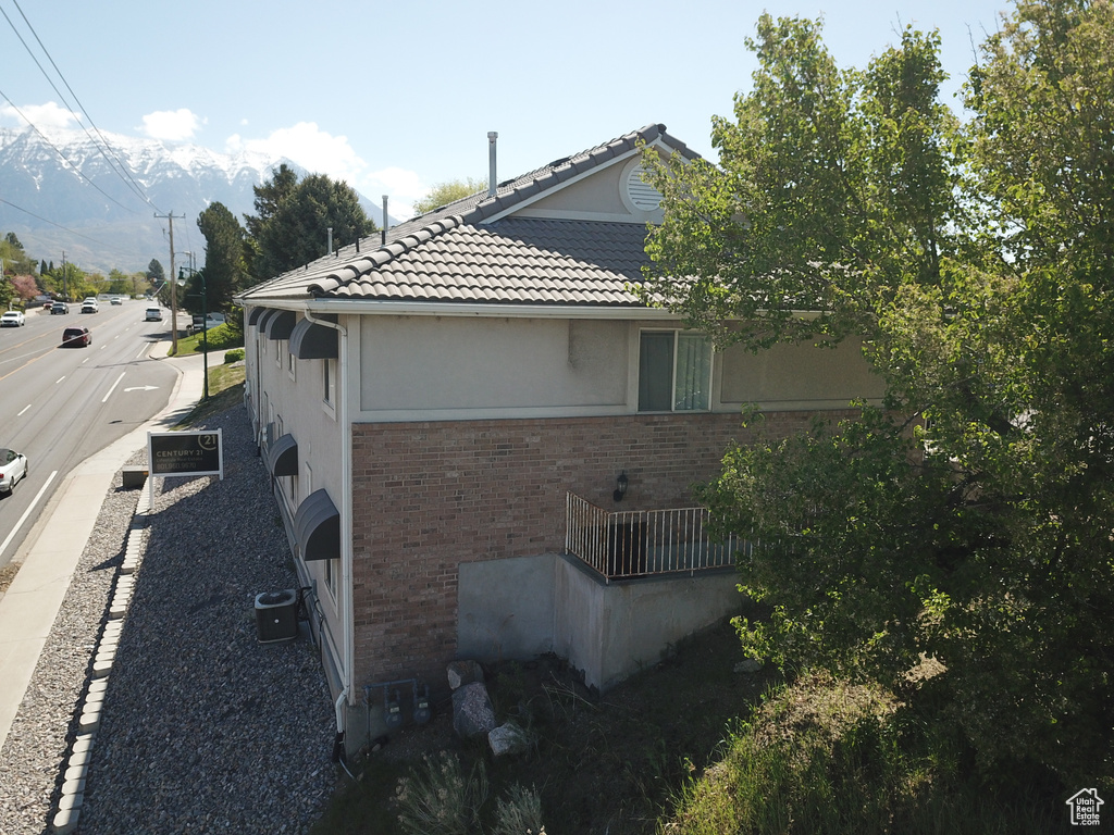 View of home's exterior with brick siding, central AC unit, stucco siding, and a tiled roof