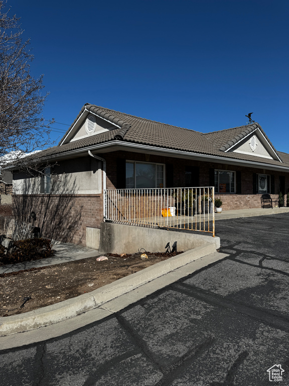 Single story home with brick siding, covered porch, and a tile roof