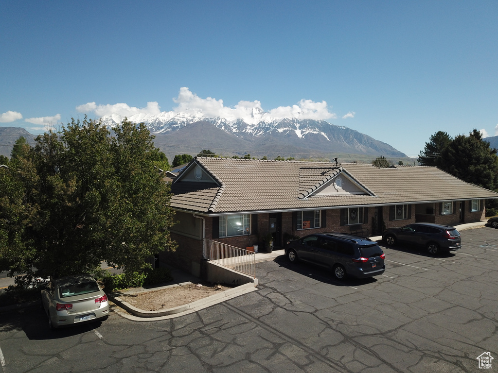 View of front of property with a mountain view, a tiled roof, and uncovered parking