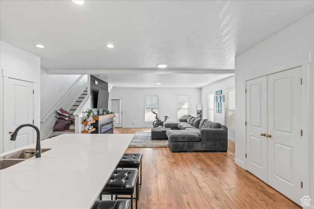 Living area with stairs, recessed lighting, light wood finished floors, and baseboards