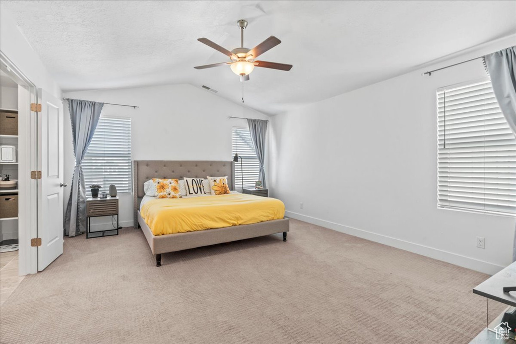 Carpeted bedroom featuring vaulted ceiling, baseboards, and ceiling fan