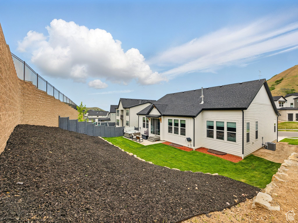 Back of house with central AC, a patio area, an outdoor hangout area, and roof with shingles