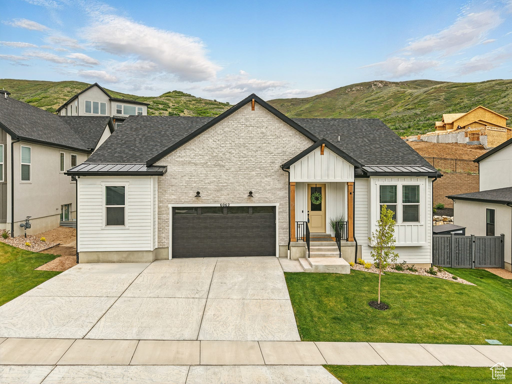 Modern farmhouse with a standing seam roof, an attached garage, metal roof, a mountain view, and driveway