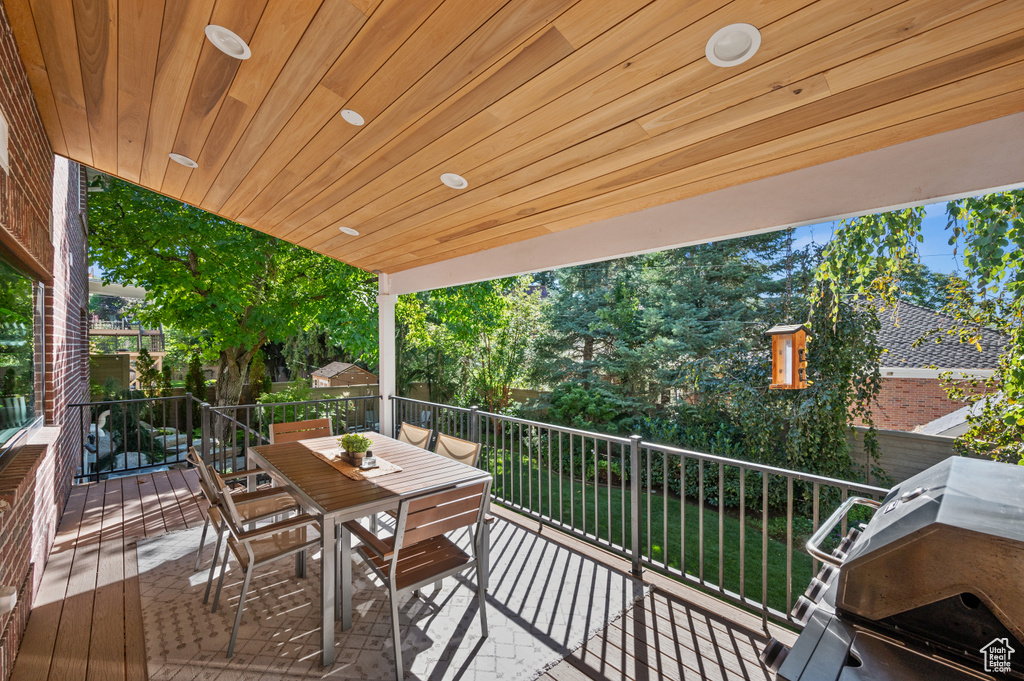 Wooden deck with area for grilling, outdoor dining space, and a yard