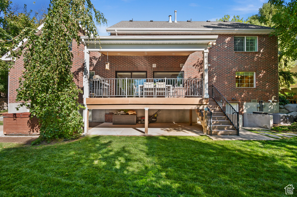 Back of house featuring brick siding, stairway, a lawn, and a patio