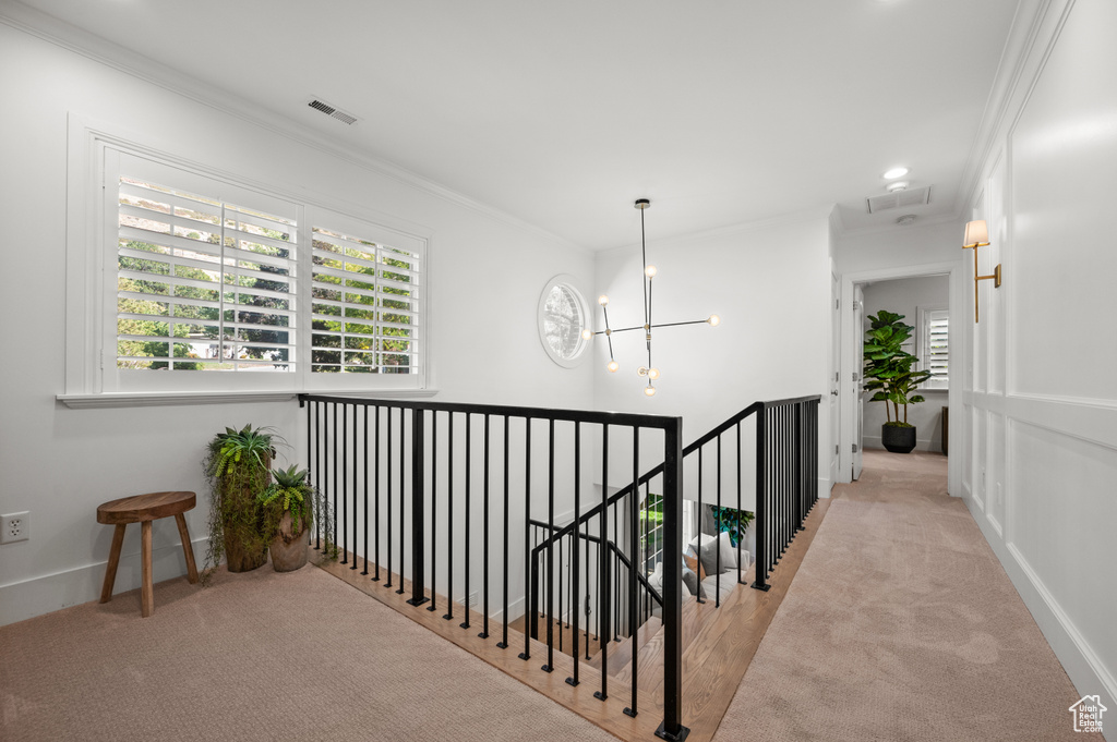 Corridor featuring an upstairs landing, visible vents, and ornamental molding