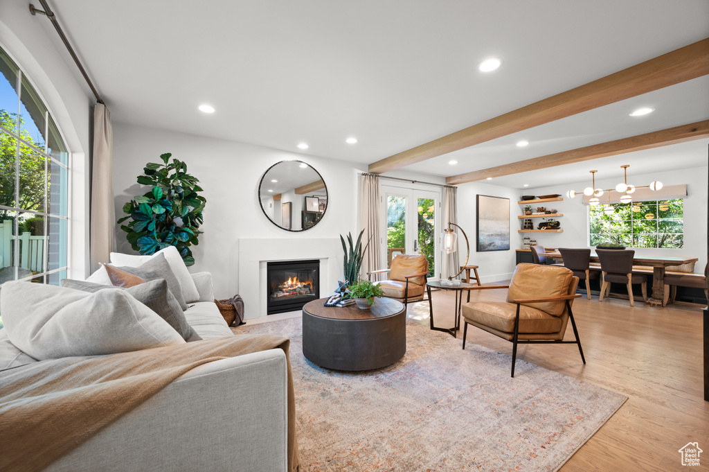Living room featuring beamed ceiling, recessed lighting, light wood-type flooring, and a glass covered fireplace