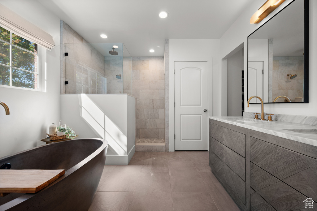 Bathroom featuring walk in shower, recessed lighting, a freestanding tub, tile patterned floors, and vanity