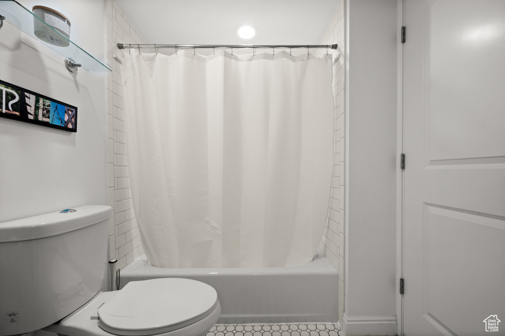 Bathroom with tile patterned floors, toilet, and shower / bathtub combination with curtain