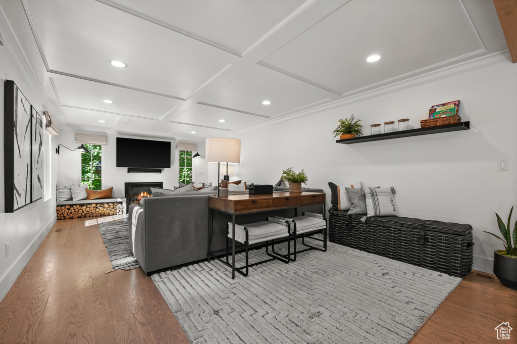 Living area with baseboards, coffered ceiling, recessed lighting, a glass covered fireplace, and light wood-type flooring