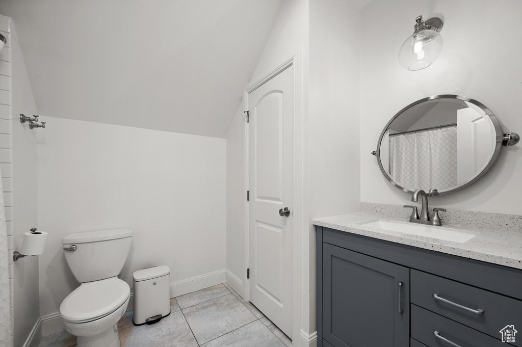 Bathroom with vanity, lofted ceiling, toilet, and baseboards