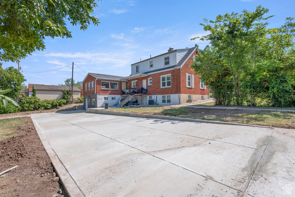 View of front of home with brick siding, driveway, and stairway