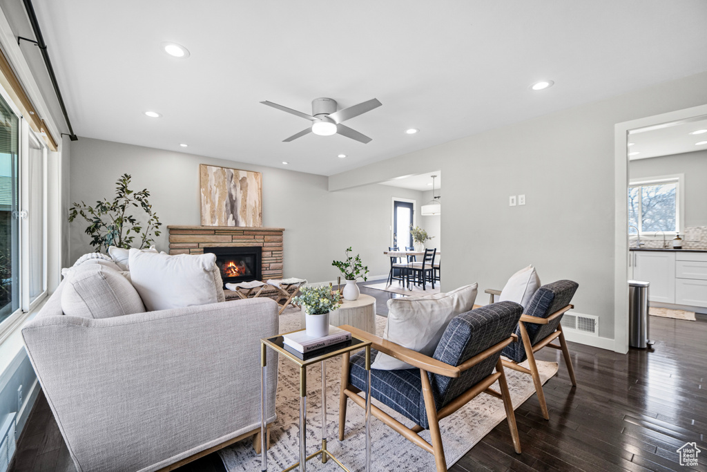 Living area featuring a stone fireplace, dark wood-type flooring, recessed lighting, and a wealth of natural light