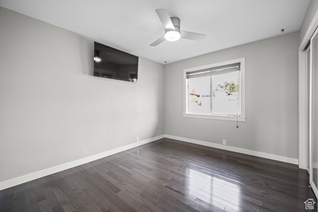 Unfurnished bedroom with ceiling fan, baseboards, and dark wood-style floors
