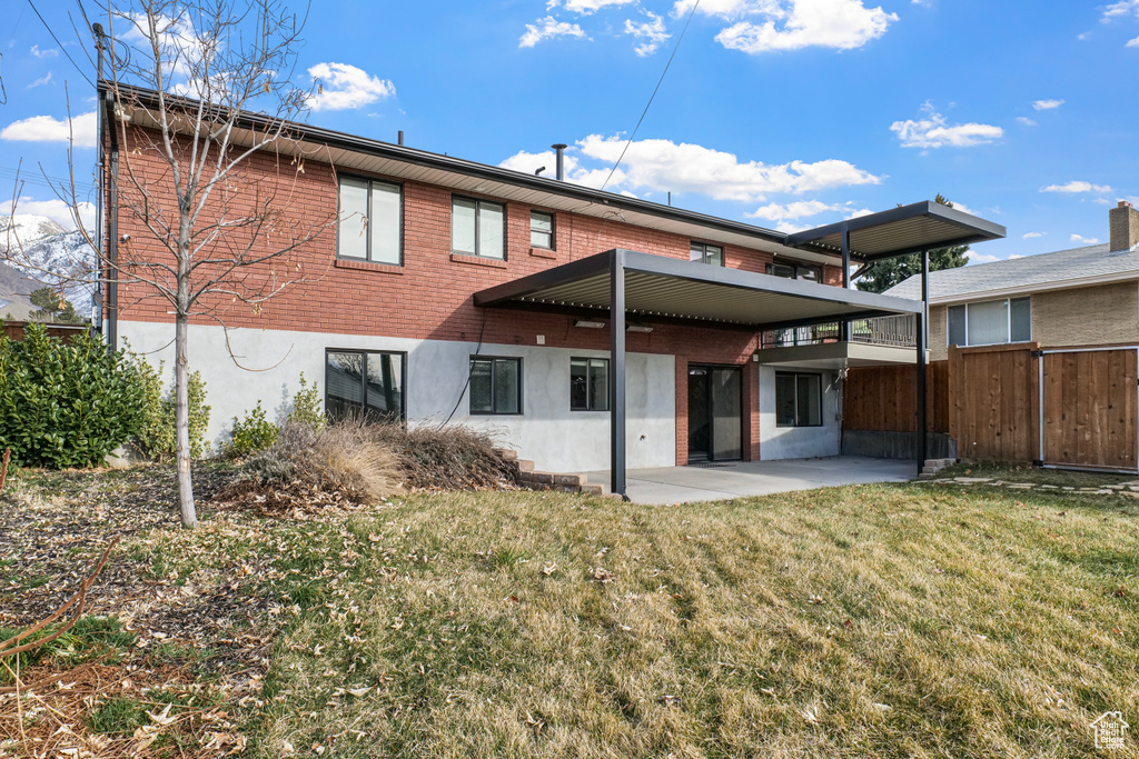 Rear view of house with brick siding, a yard, a patio, and fence
