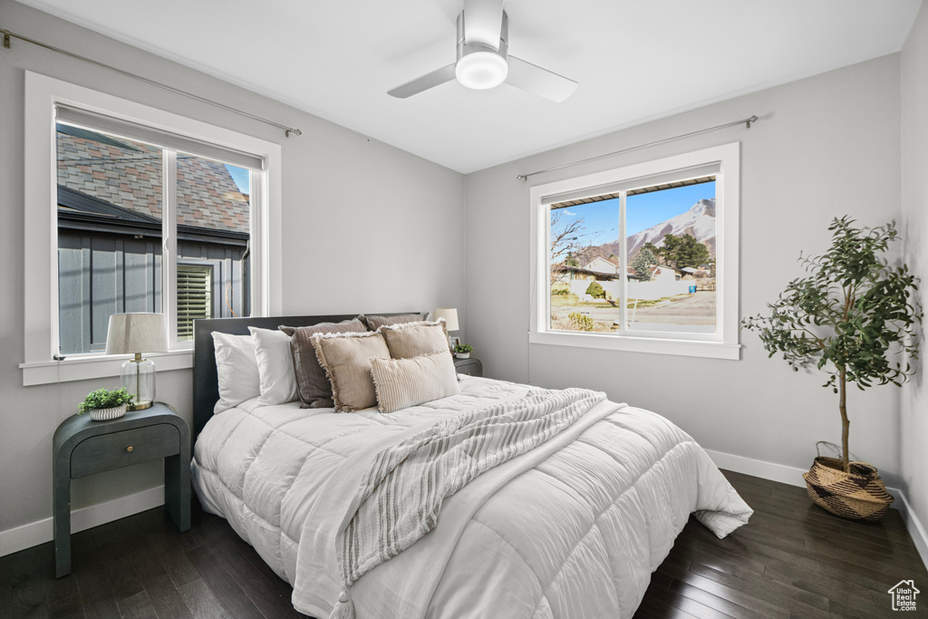 Bedroom with a ceiling fan, dark wood-type flooring, and baseboards