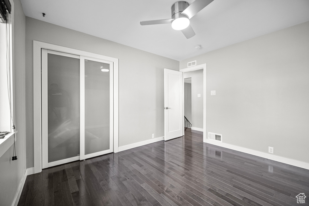 Unfurnished bedroom with baseboards, visible vents, dark wood-style flooring, and ceiling fan