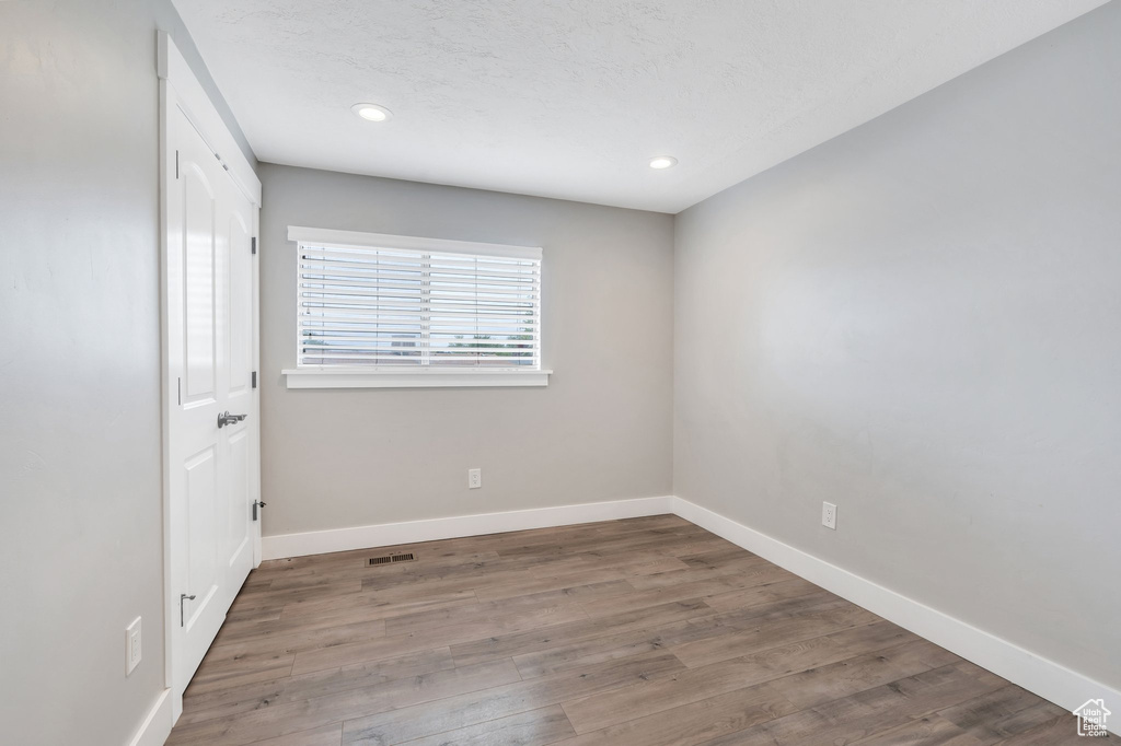 Unfurnished room with baseboards, wood finished floors, recessed lighting, and a textured ceiling