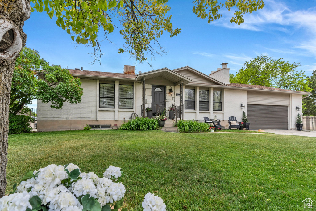 Ranch-style home with an attached garage, a front yard, and a chimney